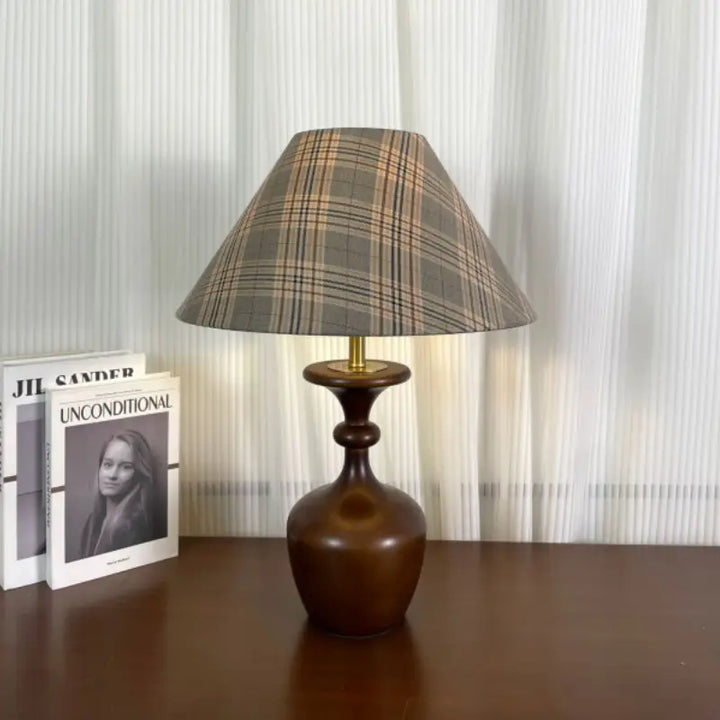 Retro accent table lamp featuring turned walnut wood base and conical plaid lampshade near fashion books
