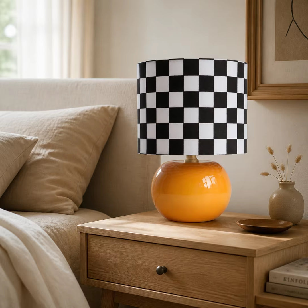 Danish modern orange base checkerboard accent lamp on travertine console table in bright sunlit home reading corner