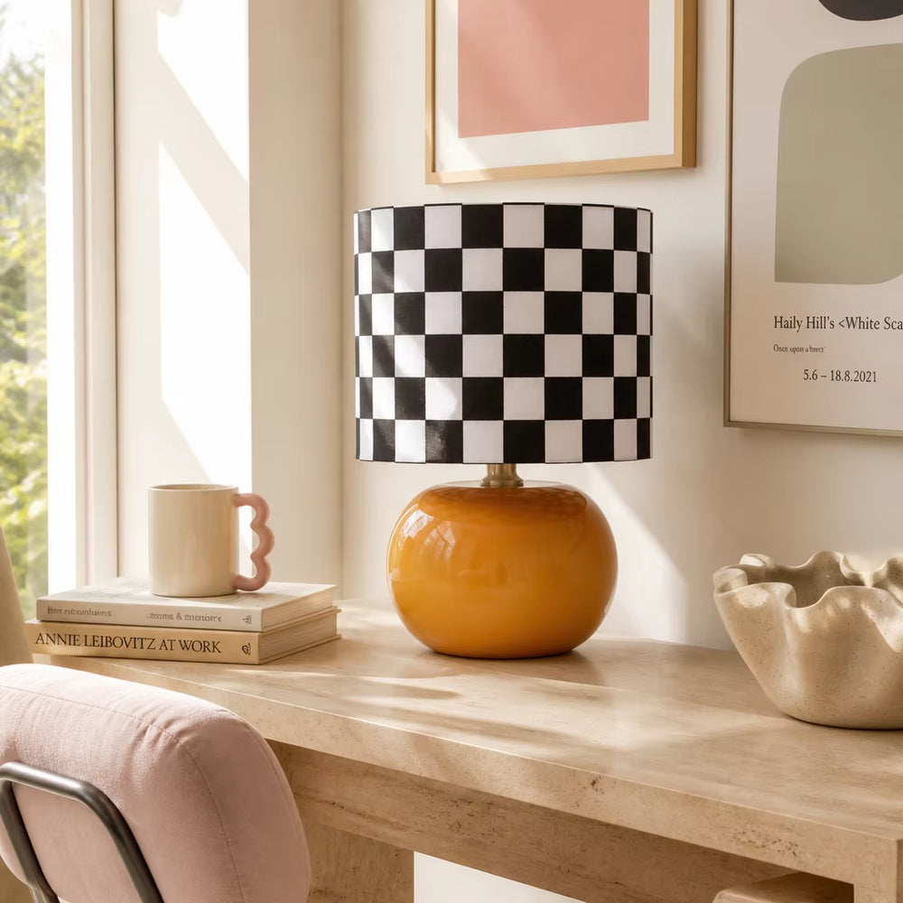Cozy bedroom nightstand styling with orange ceramic checkerboard bedside lamp, warm ambient daylight and natural linen bedding