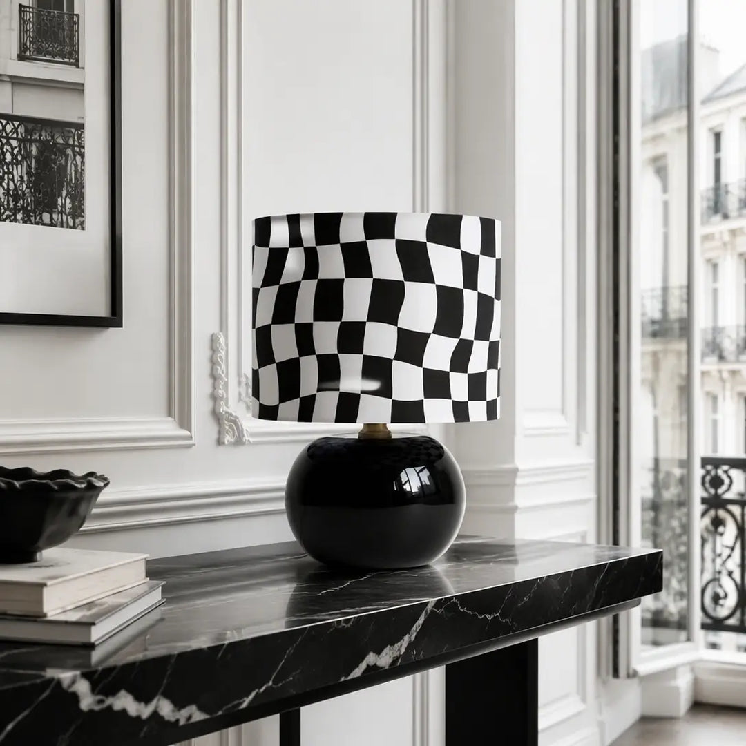 Luxury modern wavy checkerboard table lamp with glossy black porcelain orb base on marble console table in Haussmann style Parisian living room