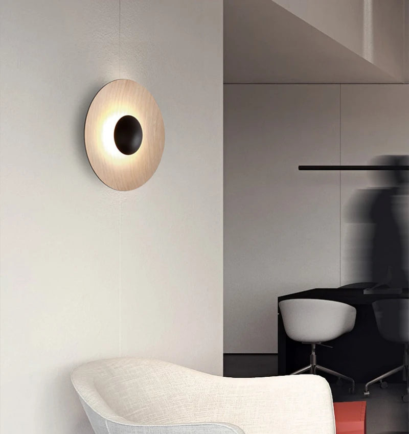 Ginger Round Wall Lamp, circular disc wall sconce with wood‑grain panel and black sphere accent for modern living area ambient lighting