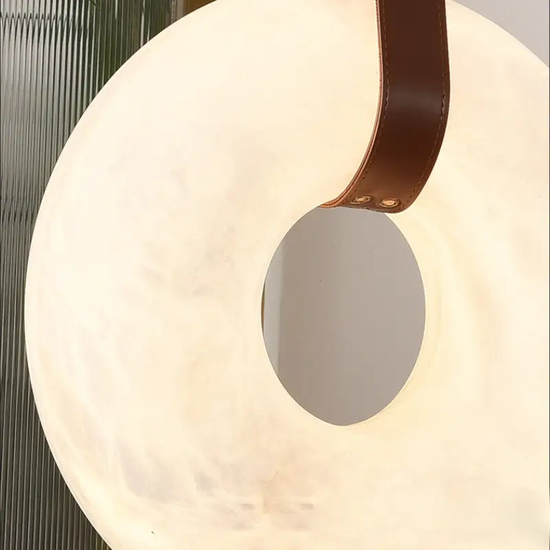 Detail view of alabaster donut hole and rivet fastener leather strap connection structure