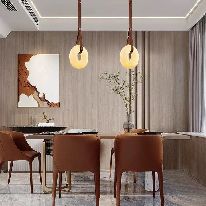 Two Leather Strap Alabaster Donut Pendant Lights installed above modern wood dining table