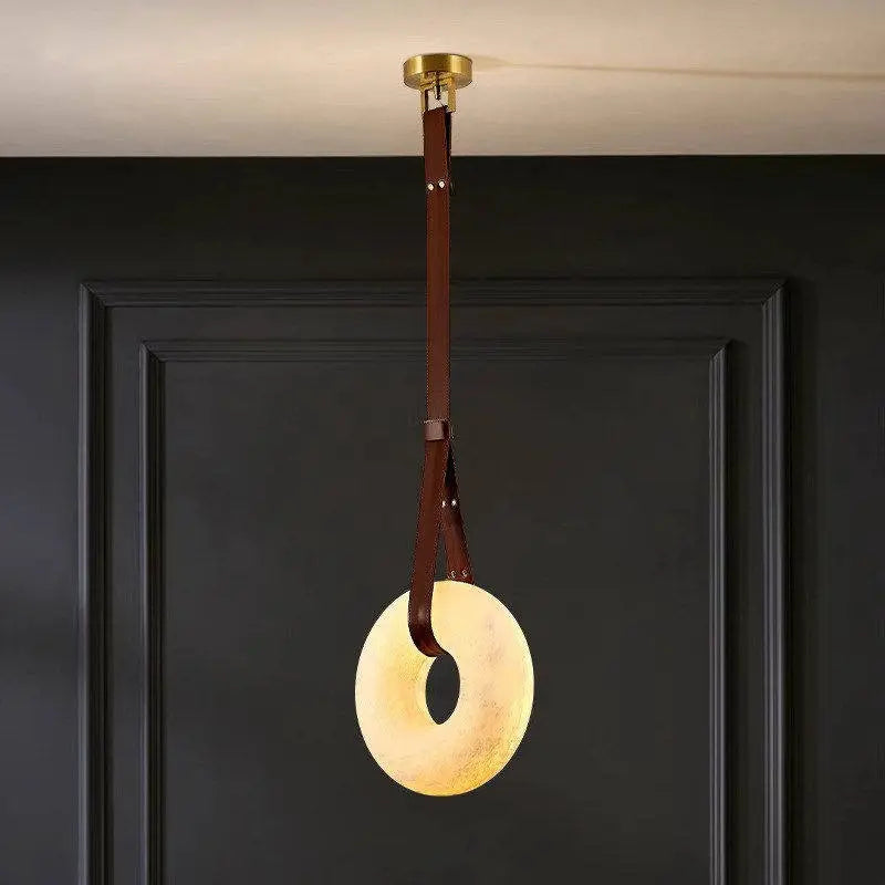 Single Leather Strap Alabaster Donut Pendant Light mounted on dark wall panel for entryway lighting