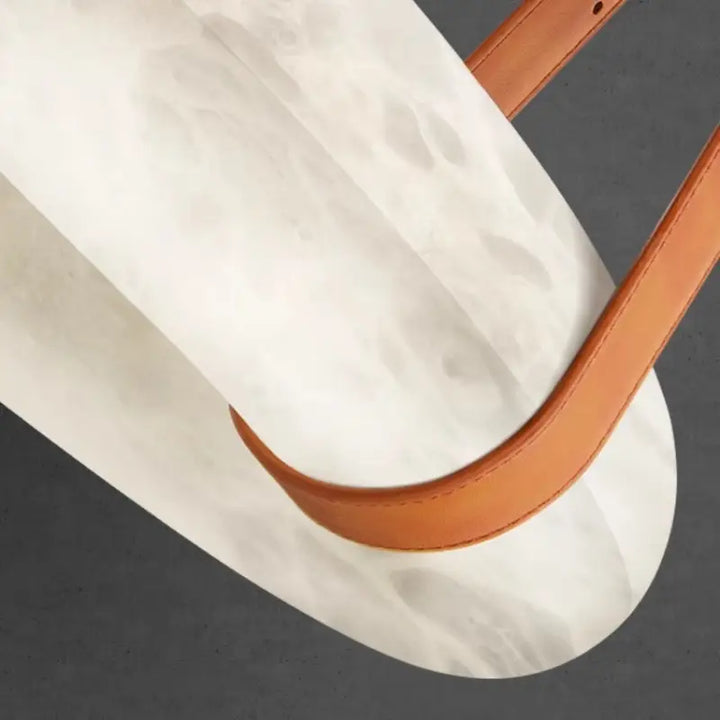 Close-up texture of natural alabaster shade and genuine leather strap for donut pendant light
