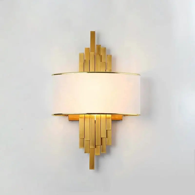 Modern luxury pipe wall lamp with glowing white fabric shade and tiered polished gold metal bars mounted on simple white wall background