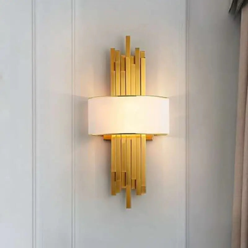 Art Deco gold stacked bar wall sconce with white fabric lampshade mounted on white wainscot panel for elegant residential interior decor