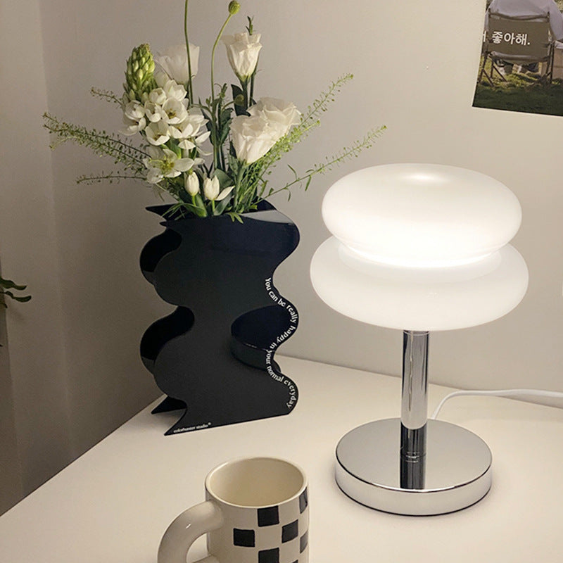 Macaron Glass Table Lamp beside a stylish black vase with flowers on a table.