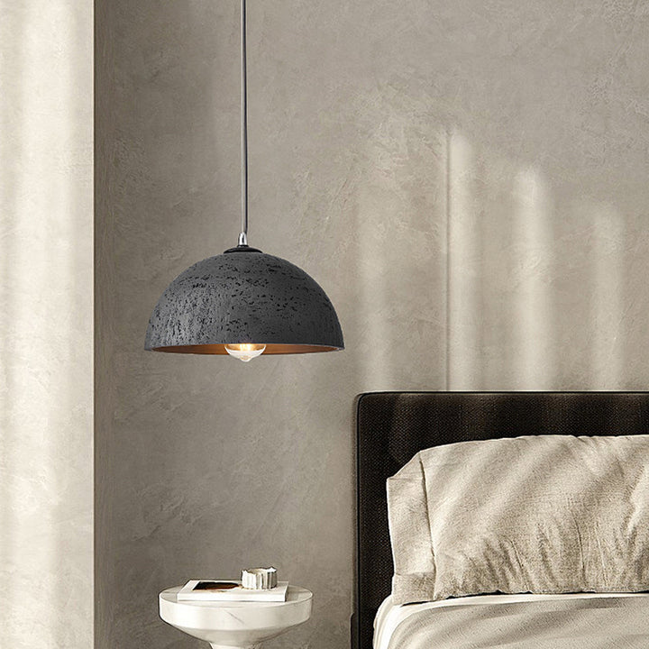 a black resin pendant lamp is near the bed