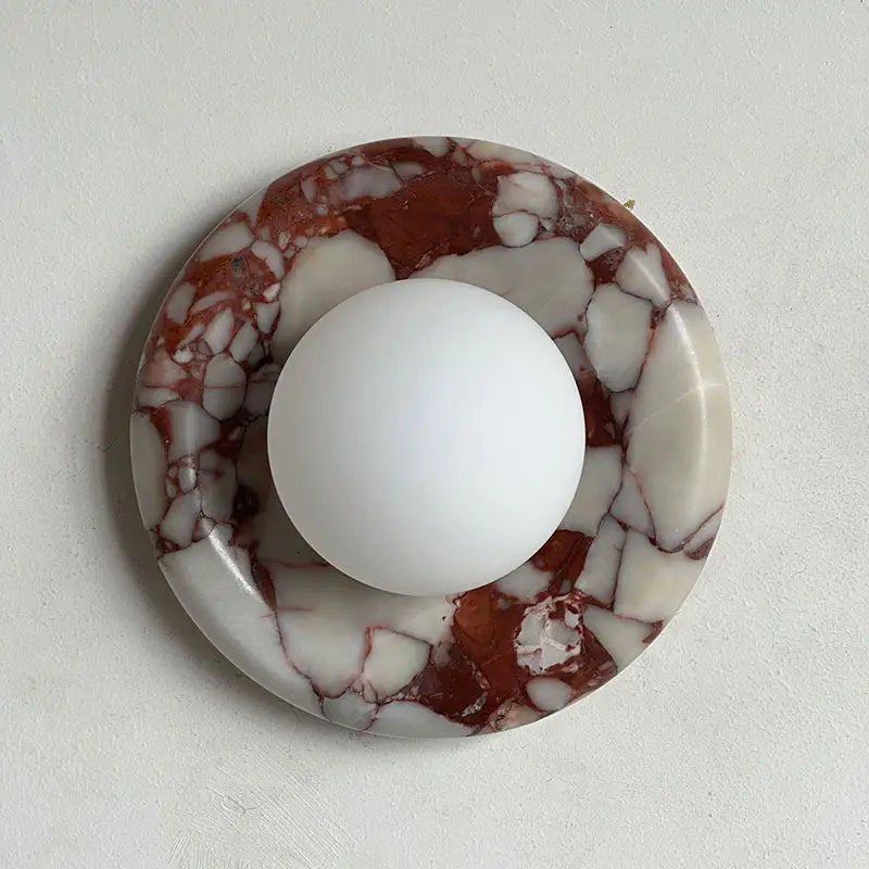 Modern Round Marble LED Wall Lamp mounted on matte plaster wall, circular red veined marble fixture with opaque glass shade