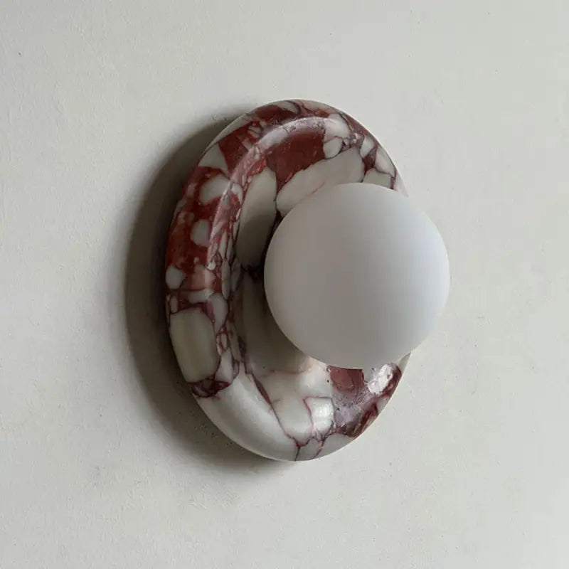 Side profile shot of Modern Round Marble LED Wall Lamp showing natural red marble stone texture and curved round backplate