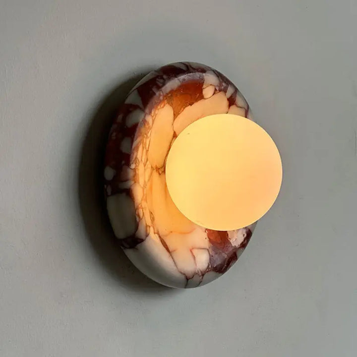 Lit Modern Round Marble LED Wall Lamp, warm soft glow through frosted glass highlighting red marble natural veining