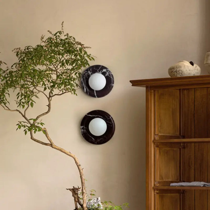 Two Modern Round Marble LED Wall Lamps paired on beige living room wall next to solid wood cabinet and bonsai tree