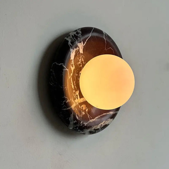 Warm lighting effect of Modern Round Marble LED Wall Lamp, glowing frosted glass contrasts dark black marble stone