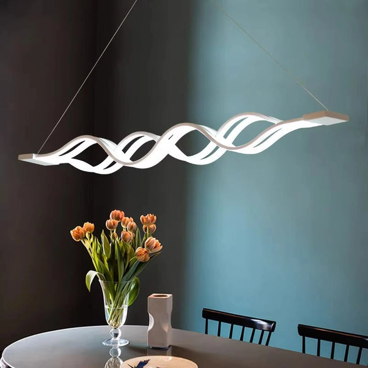 Modern Wave Pendant Light illuminating a dining table with flowers, showcasing its elegant curvature and warm ambiance.