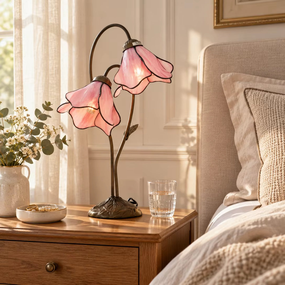 Morning sunlight illuminating pink lily glass flower desk lamp on wooden nightstand