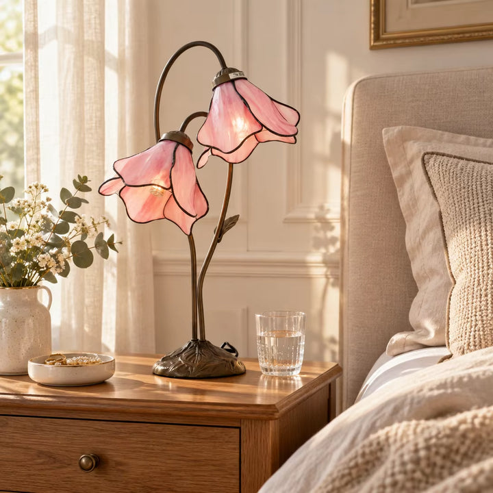 Morning sunlight illuminating pink lily glass flower desk lamp on wooden nightstand