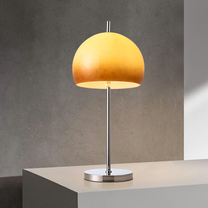 Amber sunset dome table lamp with gradient glass shade on modern display surface against textured wall