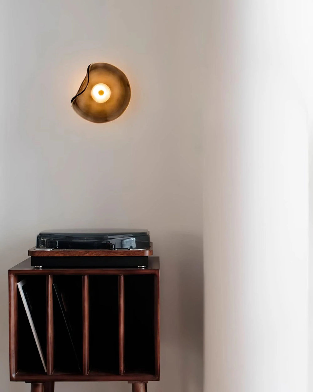 Nordic Round Glass Wall Lamp, irregular amber glass wall sconce with warm glow mounted on wall above vinyl record cabinet