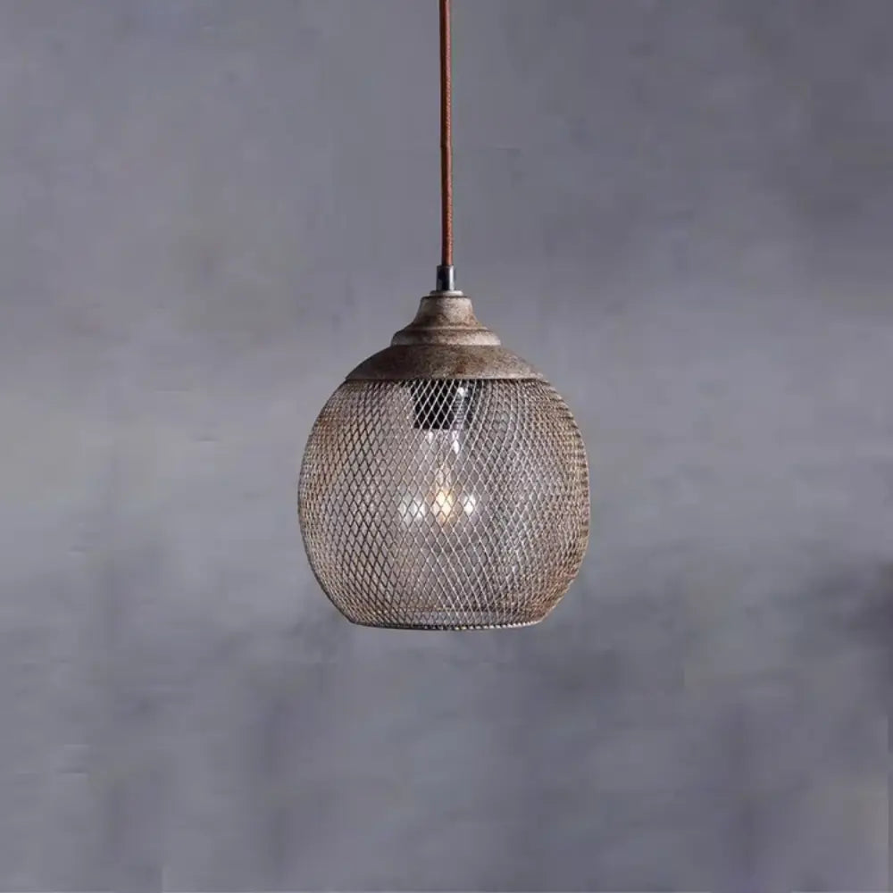 Woven wire mesh pendant light with warm glowing bulb against textured grey wall