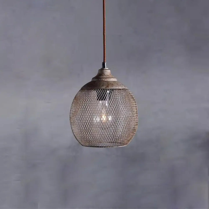 Woven wire mesh pendant light with warm glowing bulb against textured grey wall