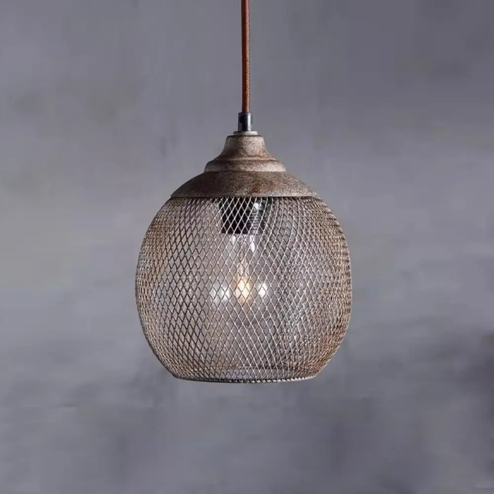 Vintage industrial mesh pendant lamp illuminated with warm ambient light against grey wall