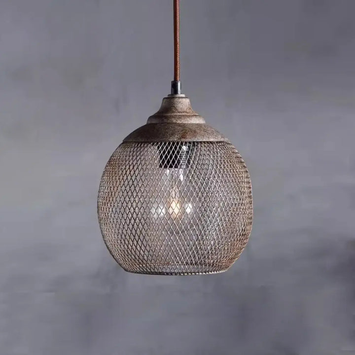 Vintage industrial mesh pendant lamp illuminated with warm ambient light against grey wall