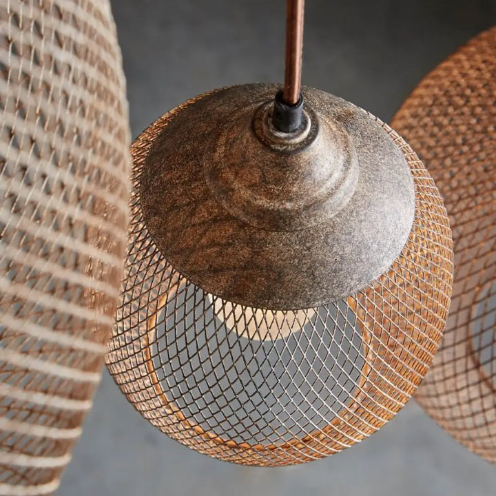 Top down macro view of woven wire mesh shade and aged bronze cap on pendant fixture