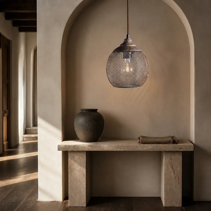 Organic modern wire mesh pendant lamp illuminated over stone entryway console table