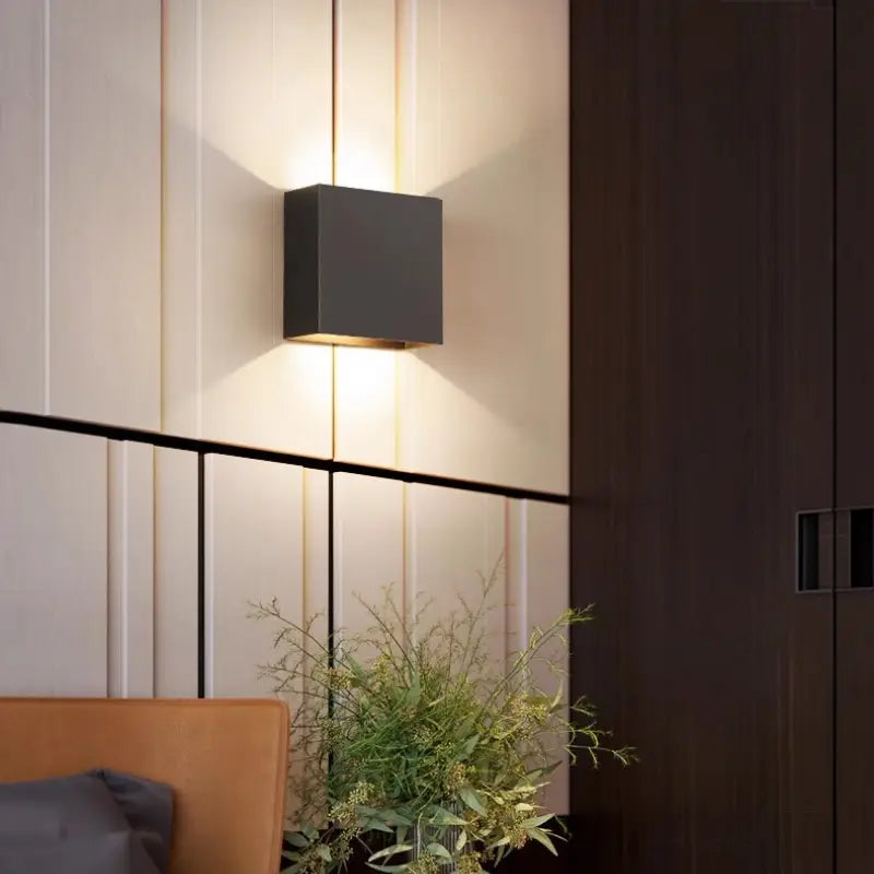 Black Volex up down LED wall sconce mounted on vertical panel wall casting layered light shadows for luxury contemporary living room interior styling