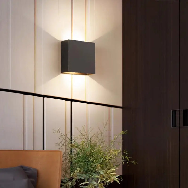 Black Volex up down LED wall sconce mounted on vertical panel wall casting layered light shadows for luxury contemporary living room interior styling