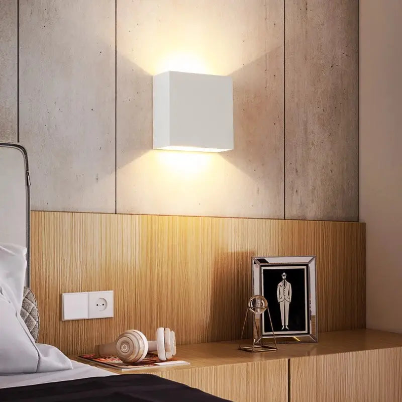 White Volex cube LED wall sconce mounted above bedroom bedside casting soft dual up down glow for minimalist bedroom ambient reading lighting decor