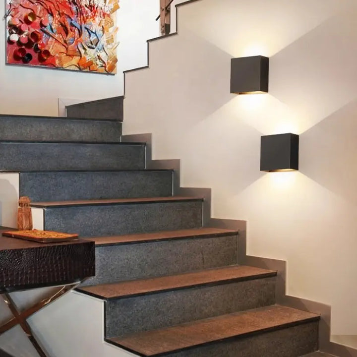 Two black Volex cube LED wall sconces installed along stairwell wall casting layered dual light shadows for residential staircase accent lighting