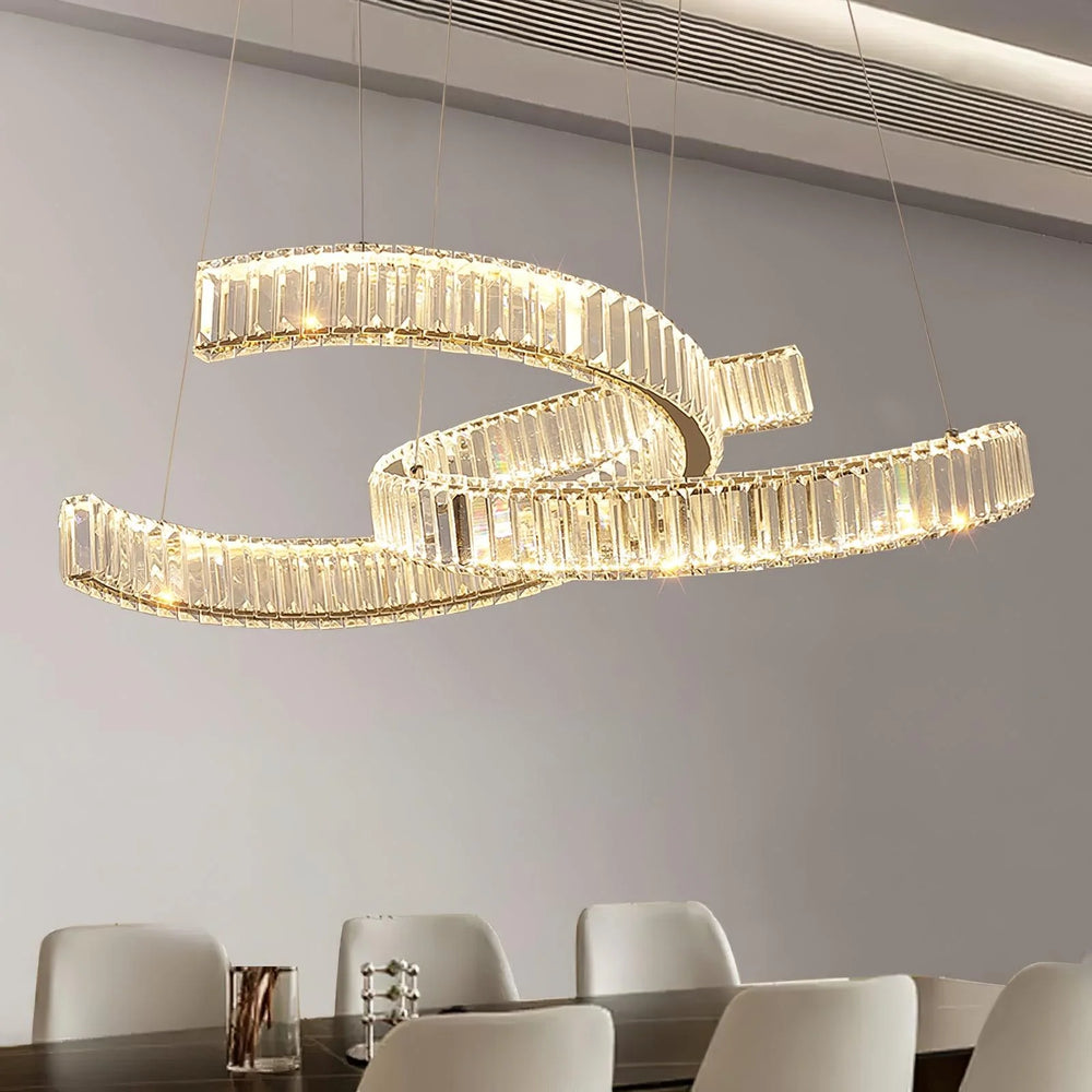 Vortex chandelier with curved crystal bands above a dining table in a modern interior with neutral tones