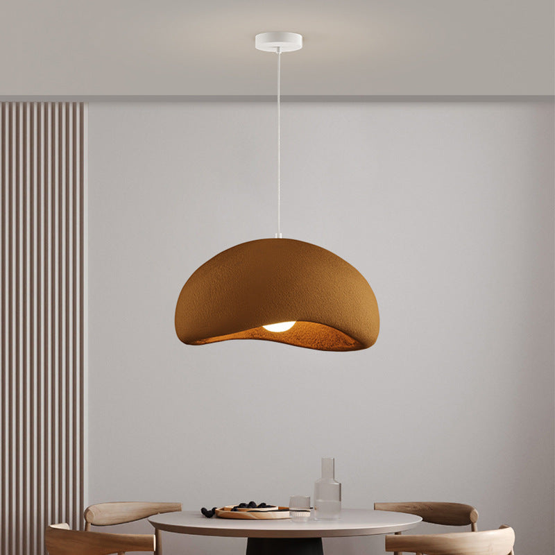 Brown wabi sabi resin pendant light above minimalist dining table